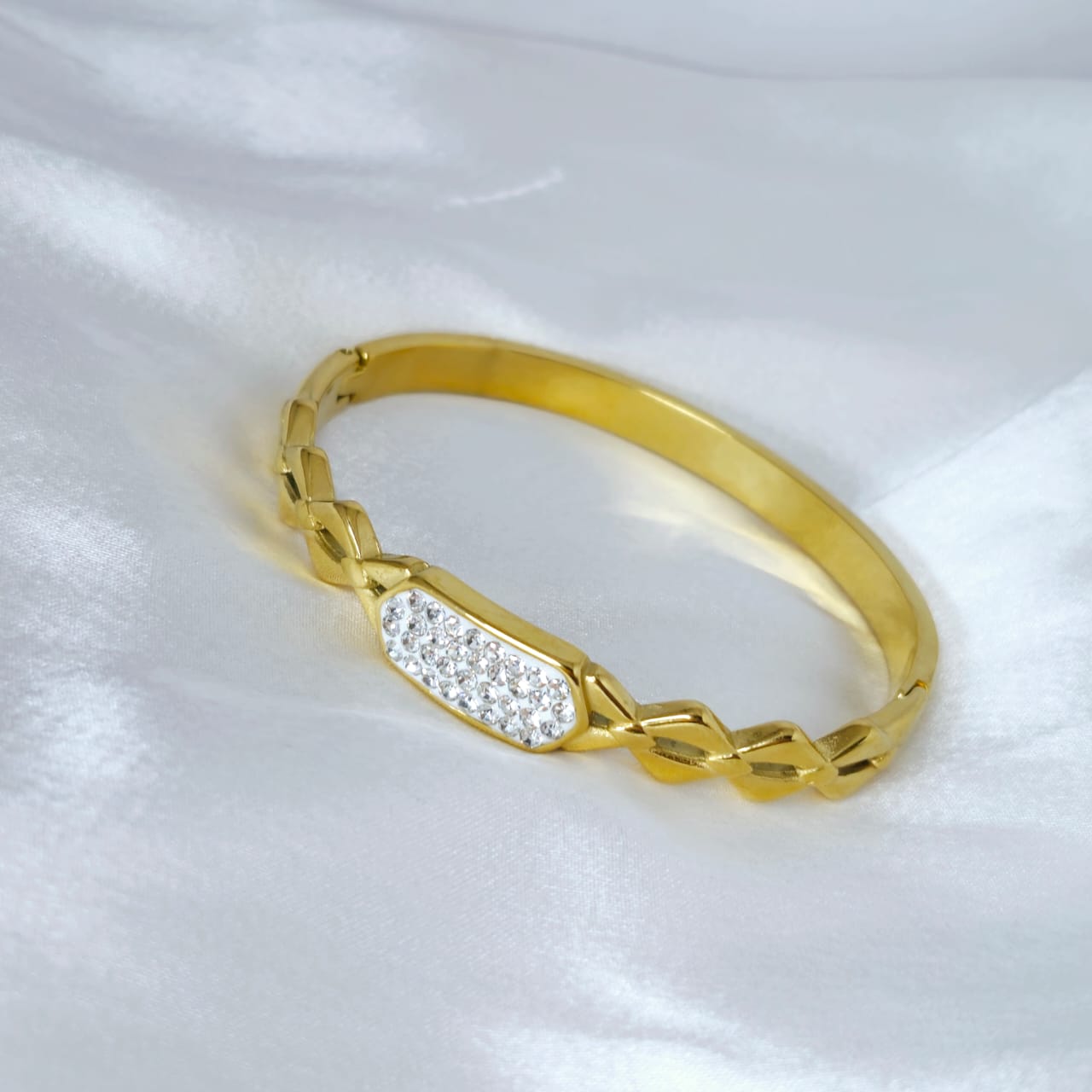 Gold bracelet with diamond accents on a white background