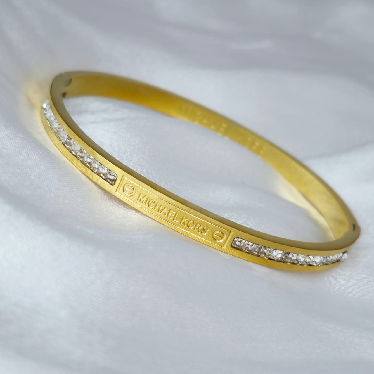 Gold bracelet with diamond accents on a white fabric background