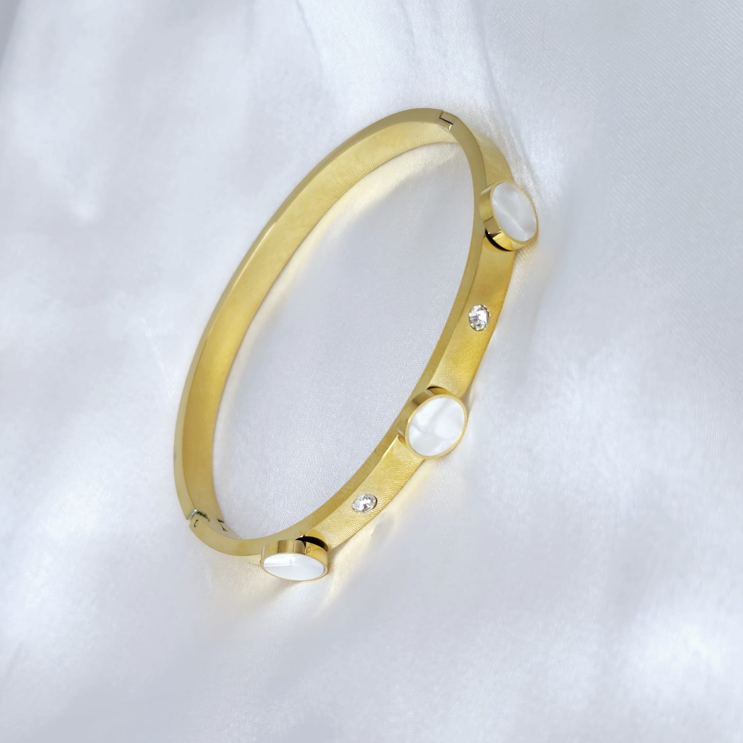 Gold bracelet with embedded stones on a white background