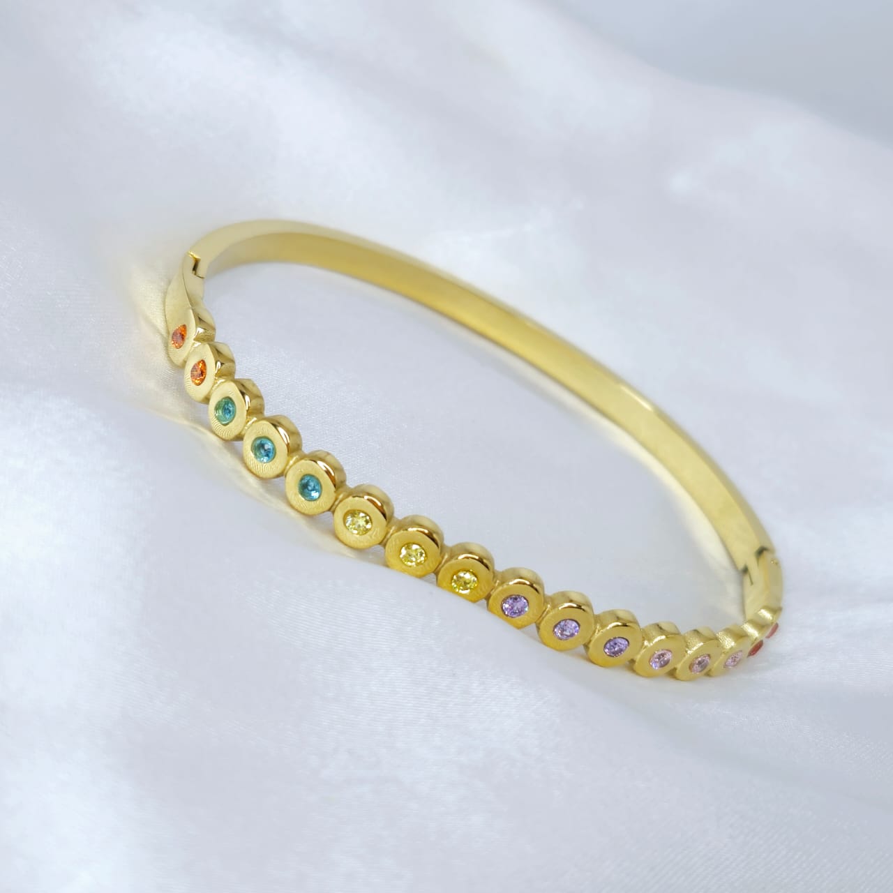 Gold bracelet with colorful beads on a white background