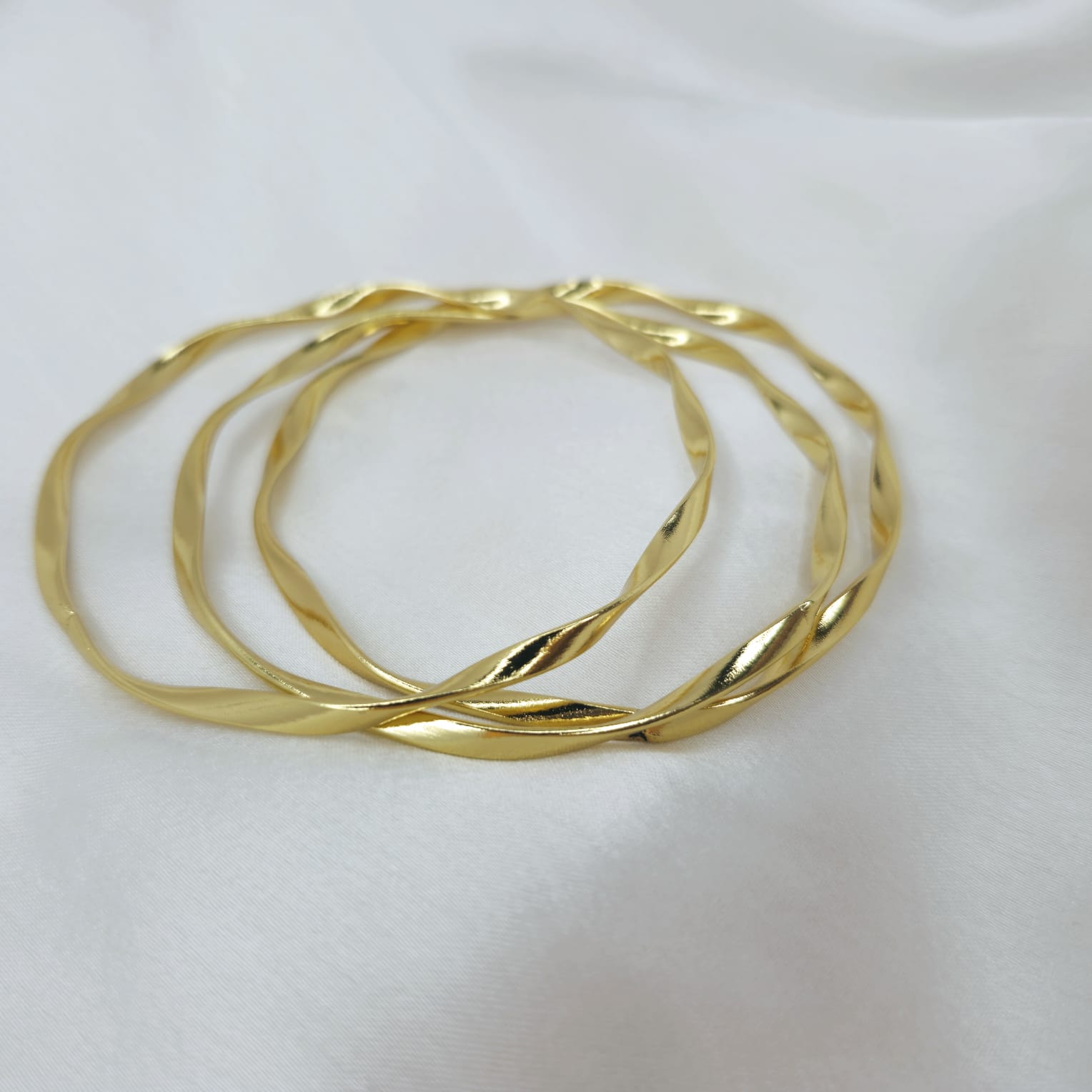 Three gold bangles on a white background