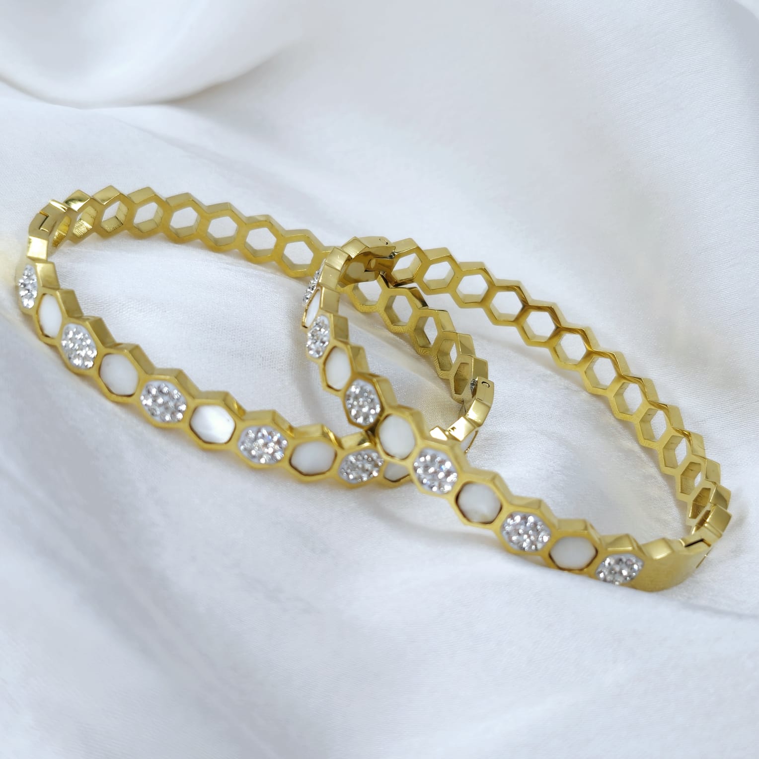 Gold bracelet with honeycomb design and embedded crystals on a white background