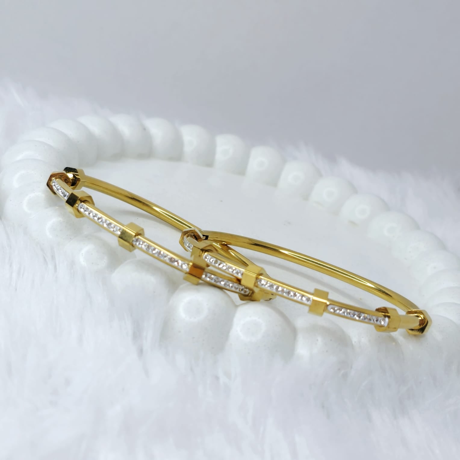 Gold bracelet with clear stones on a textured white surface