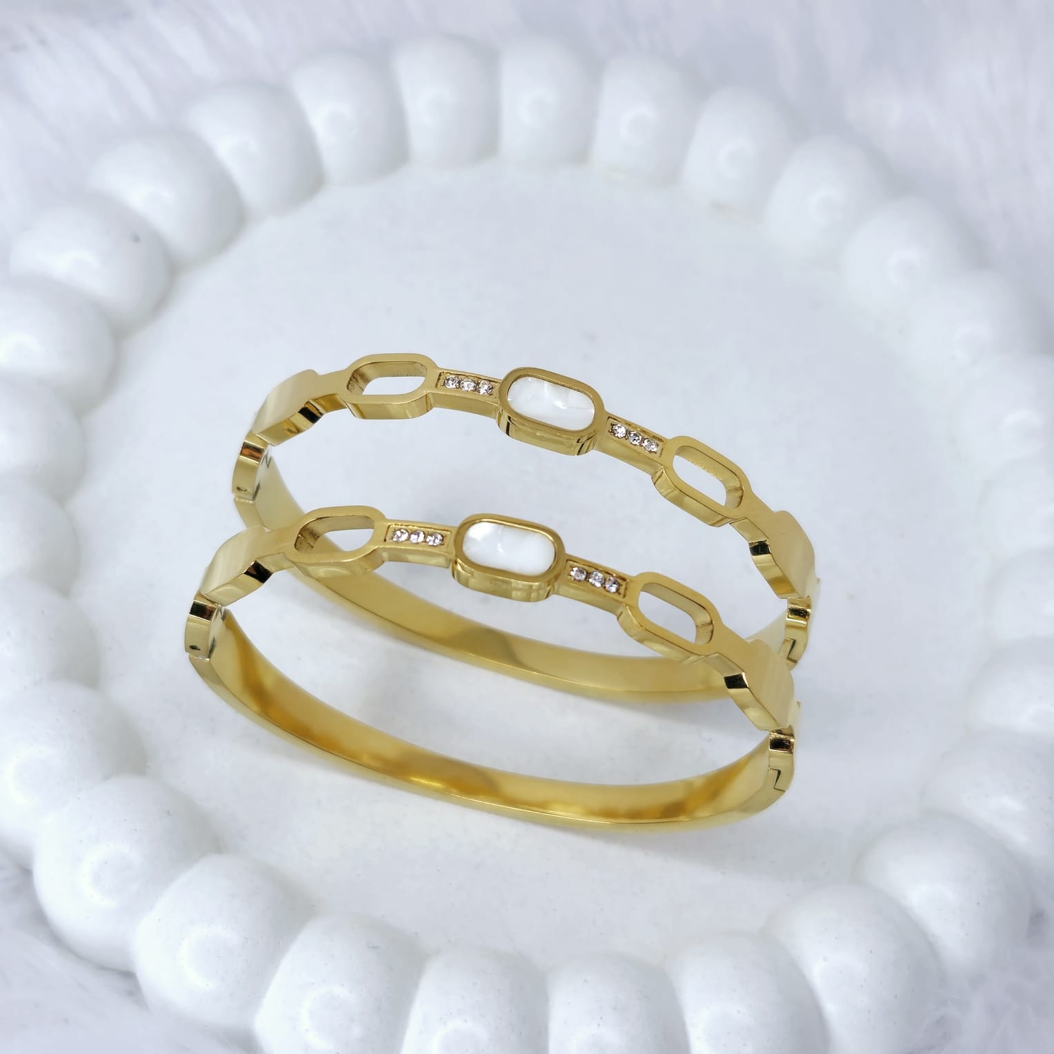 Gold bracelet with interlocking links on a textured white surface