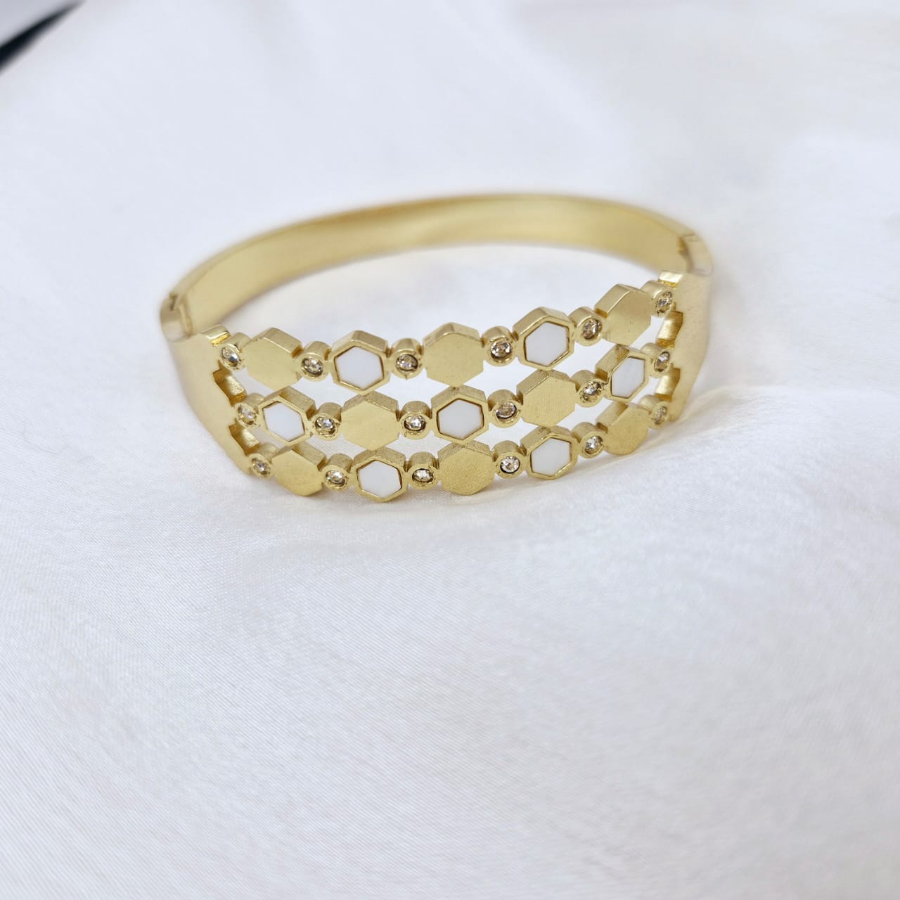 Gold bracelet with geometric design on a white background
