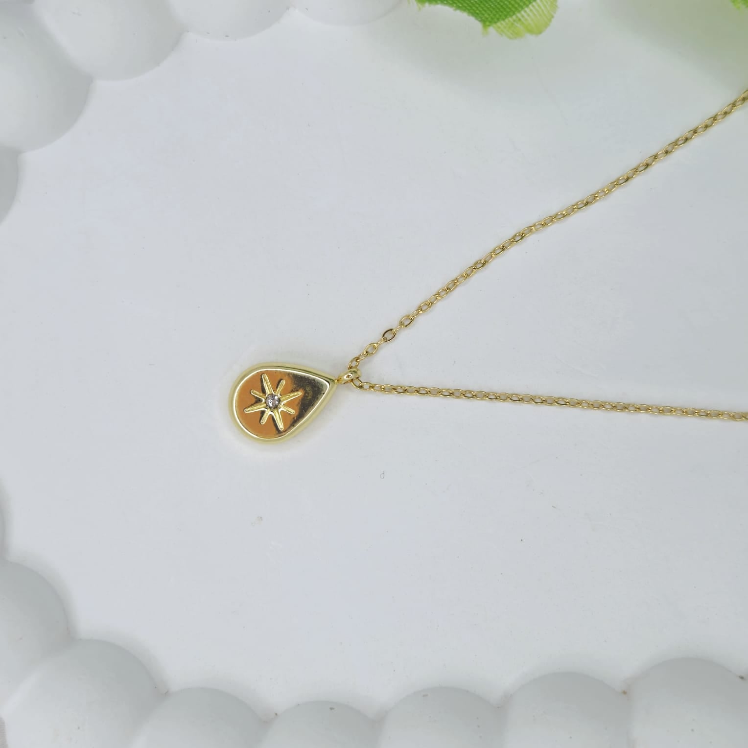 Gold necklace with a heart-shaped pendant on a white background