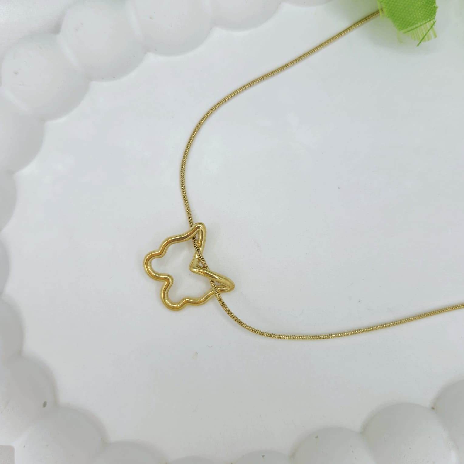 Gold butterfly necklace on a white textured surface