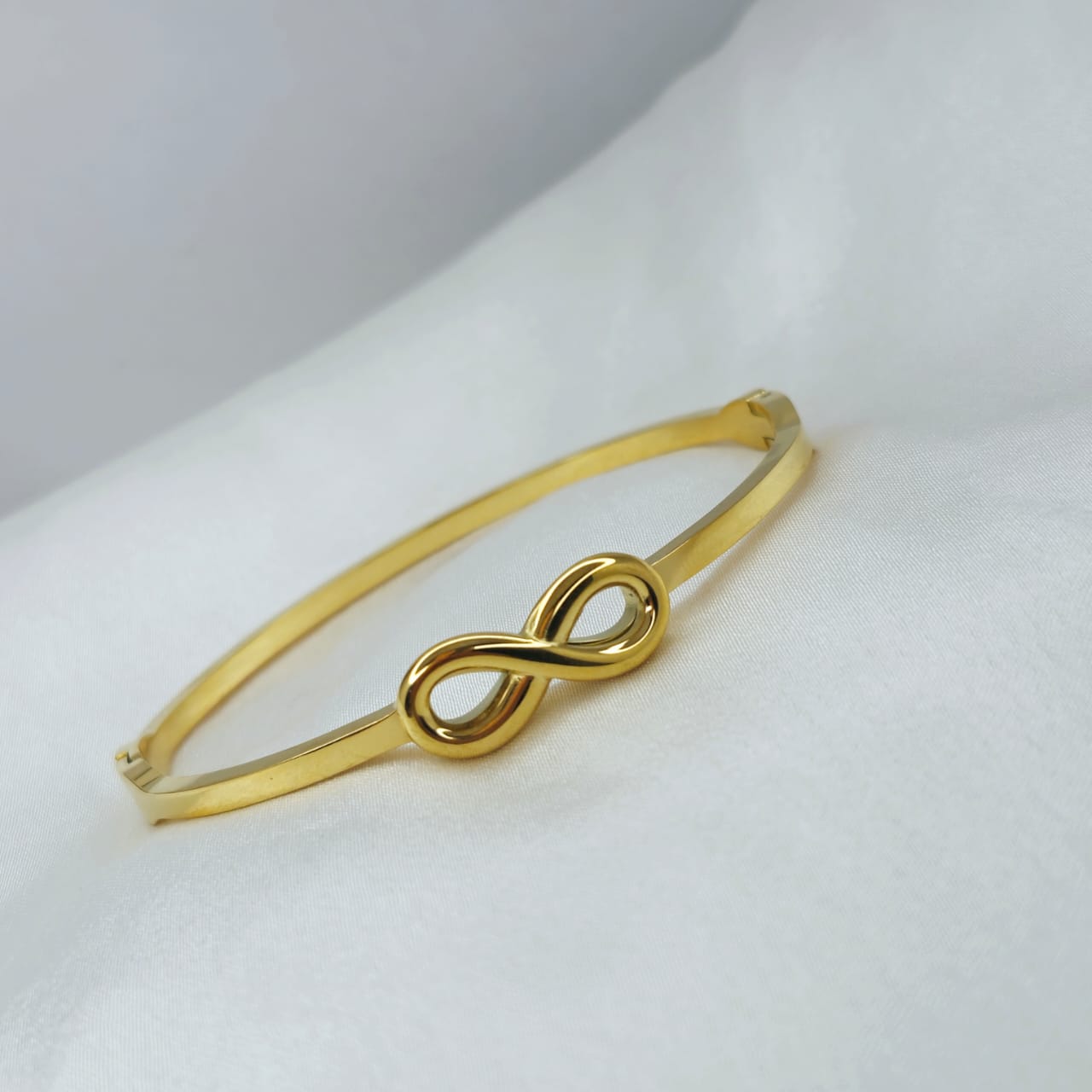 Gold bracelet with an infinity symbol on a white background