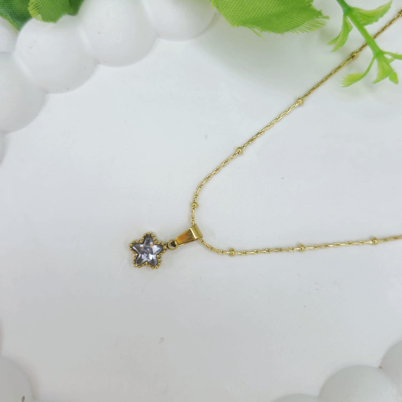 Gold necklace with a star-shaped pendant on a white background