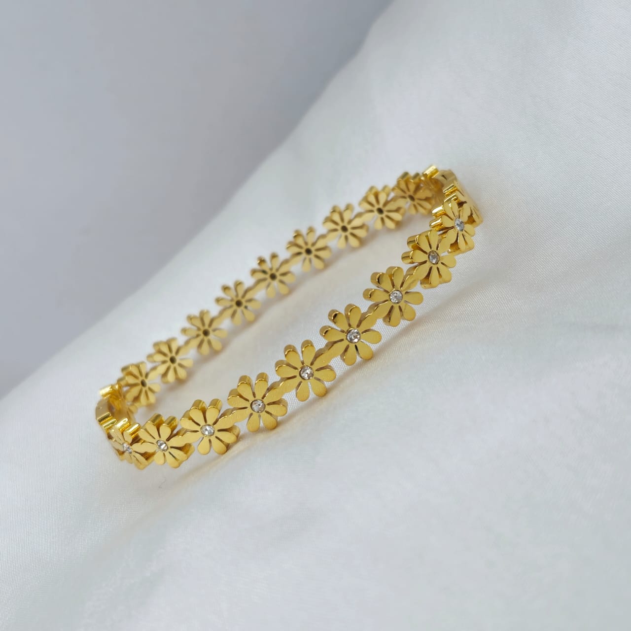Gold bracelet with floral design on a white surface