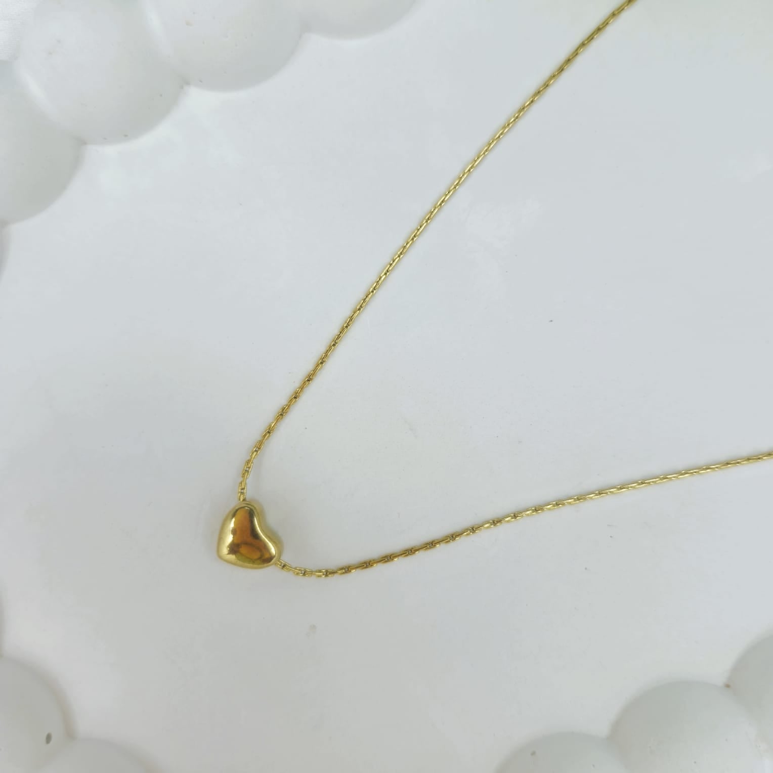 Gold heart-shaped pendant necklace on a white background