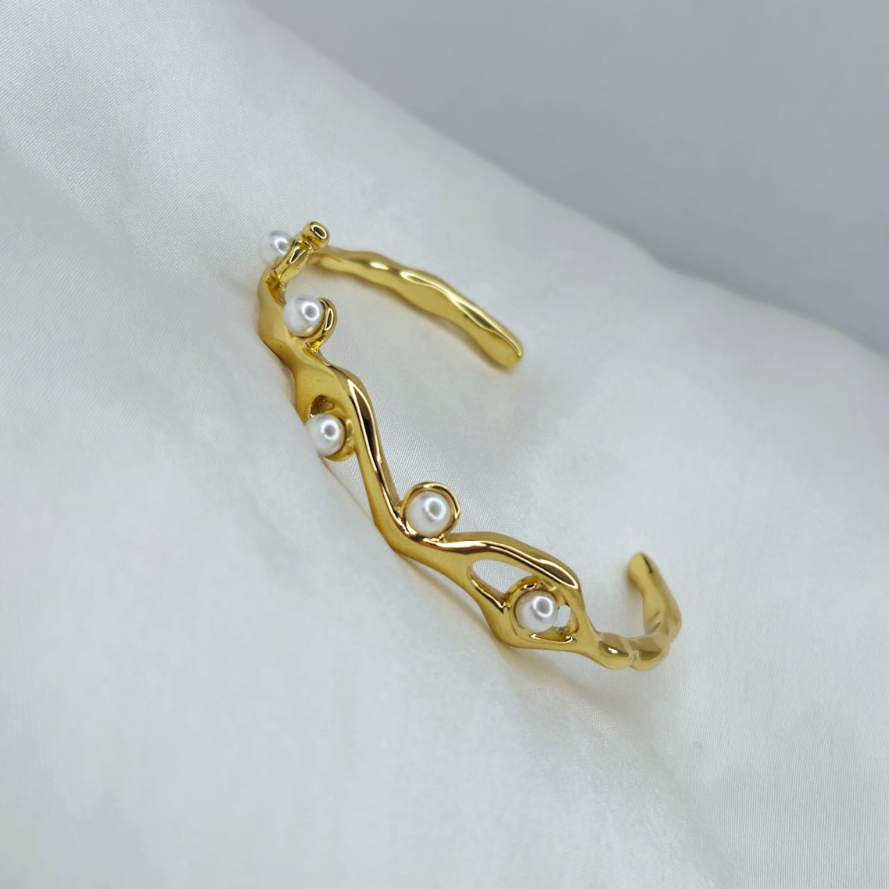 Gold bracelet with pearls on a white surface